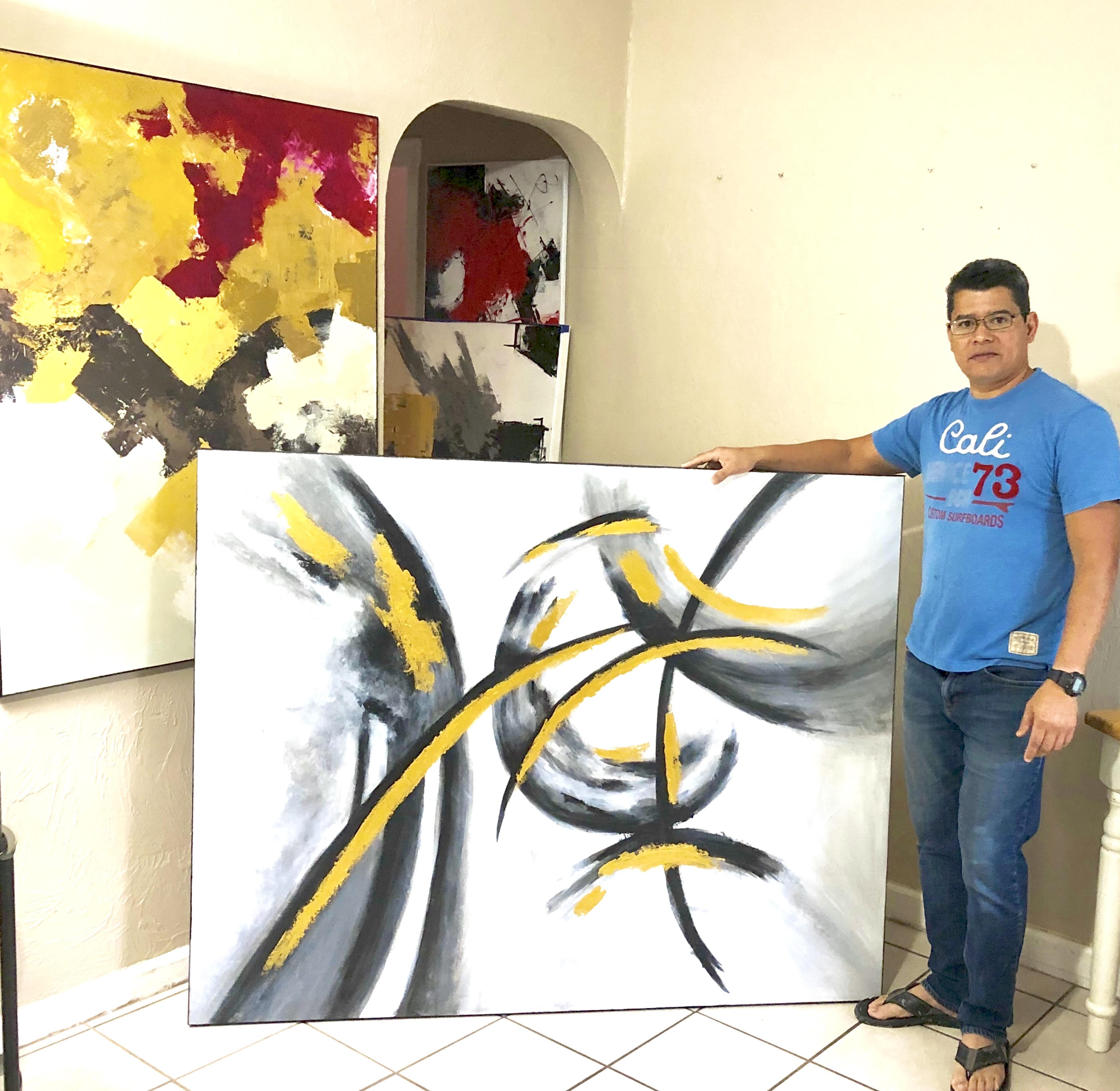 Roland Calix standing beside one of his large abstract paintings